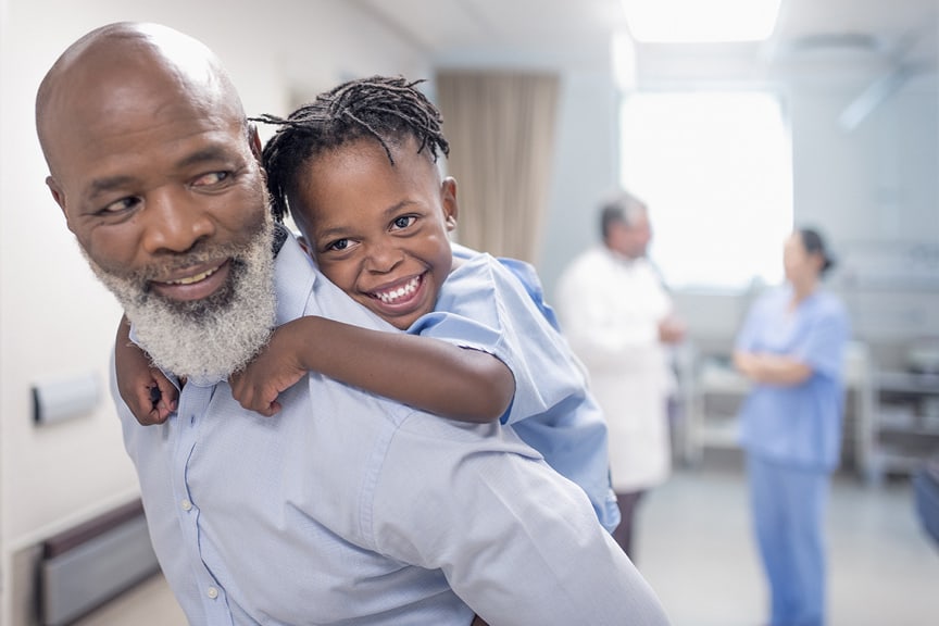 Grandfather gives grandson piggy back ride at health care center